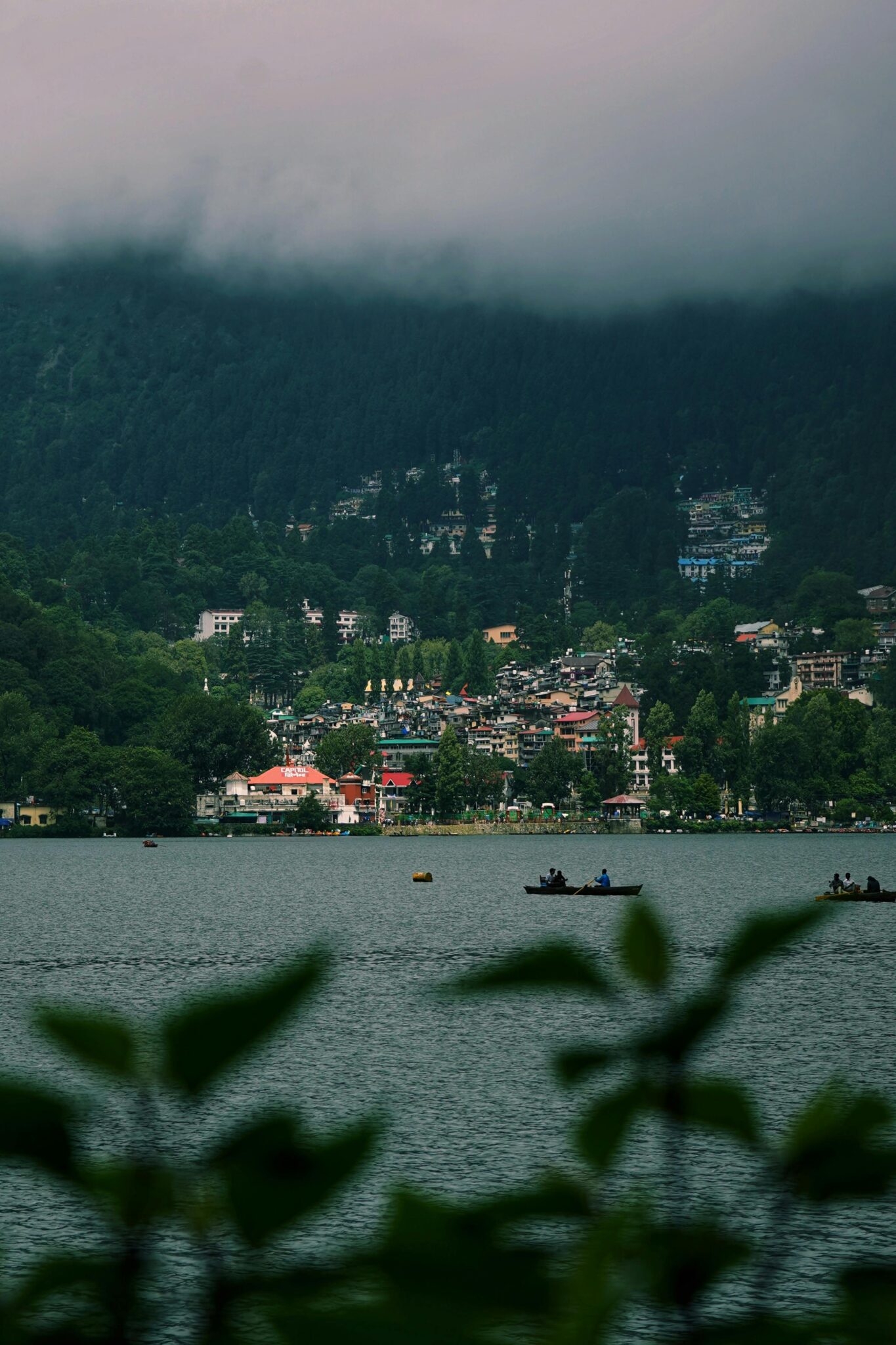 Picturesque landscape of Nainital Lake with misty mountains and lush greenery.